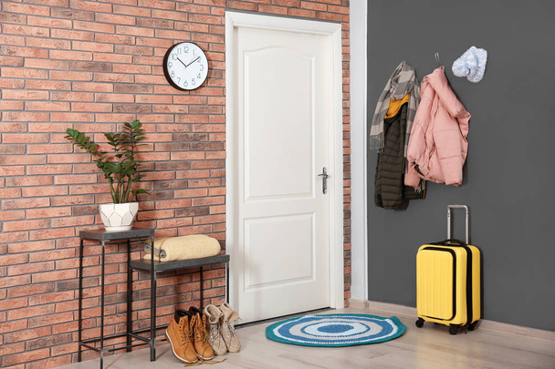 Modern hallway interior with stylish furniture, suitcase and clothes on wall - Valokuva, kuva