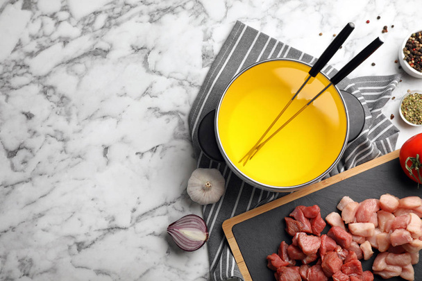 Flat lay composition with fondue pot, raw meat and space for text on marble background - Fotoğraf, Görsel