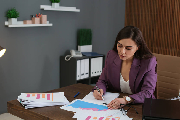 Beautiful businesswoman working with documents at table in office - Photo, Image