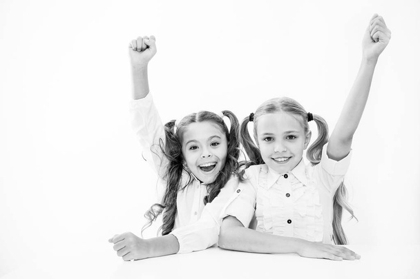 Schoolgirls happy keep hands up while sit at desk white background. Win school quiz. They know right answer. Schoolgirls emotional cheerful celebrate victory. Winners team. Teamwork and leadership - Photo, image