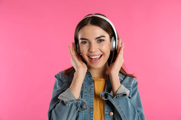 Beautiful young woman listening to music with headphones on color background - Φωτογραφία, εικόνα