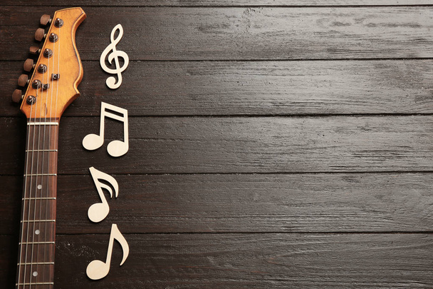 Music notes and guitar neck on wooden background, top view. Space for text - Foto, Imagem