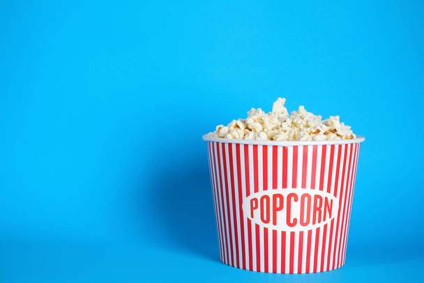 Bucket of fresh tasty popcorn on color background, space for text. Cinema snack - Fotografie, Obrázek