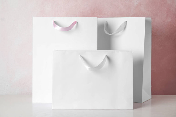 Paper shopping bags on table against color background. Mock up for design - Foto, Imagem