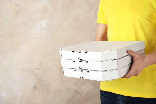 Young man with pizza boxes on color background, space for text. Food delivery service - Fotó, kép
