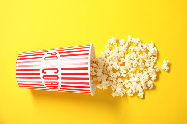 Cup with fresh tasty popcorn on color background, top view. Cinema snack - Foto, Imagen