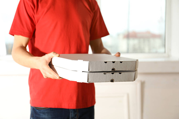 Young man with pizza boxes indoors, space for text. Food delivery service - 写真・画像