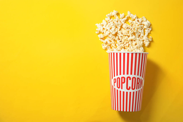 Fresh tasty popcorn and cup on color background, top view with space for text. Cinema snack - Foto, afbeelding