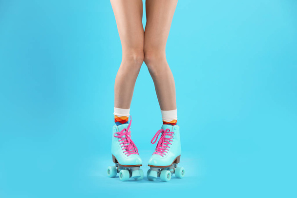 Young woman with retro roller skates on color background, closeup - Фото, изображение