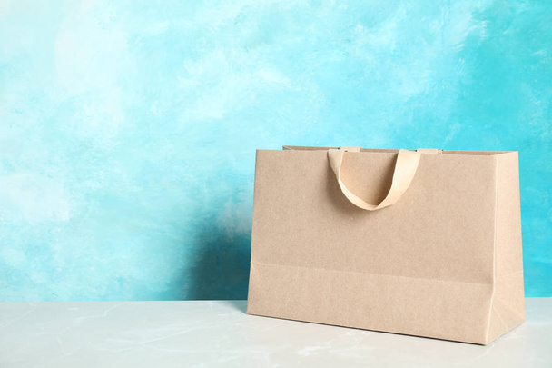 Paper shopping bag on table against color background. Mock up for design - Фото, изображение