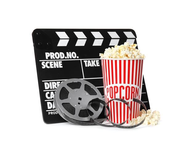 Popcorn, clapper and reel isolated on white. Cinema snack - Photo, Image