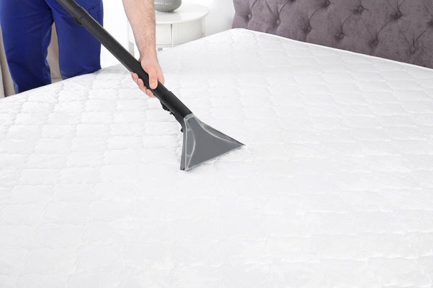 Man disinfecting mattress with vacuum cleaner, closeup. Space for text - Foto, afbeelding