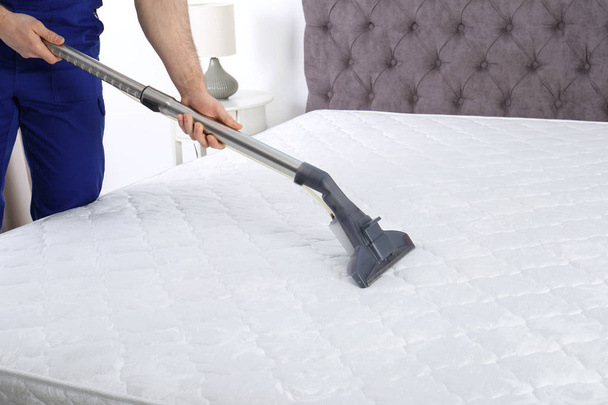 Man disinfecting mattress with vacuum cleaner, closeup - Photo, image