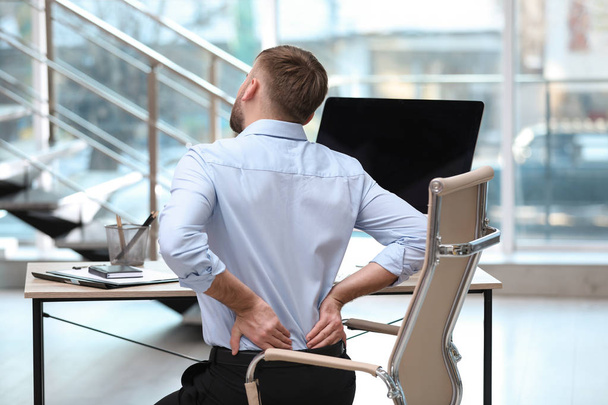 Liikemies, joka kärsii selkäkivuista työpaikalla
 - Valokuva, kuva