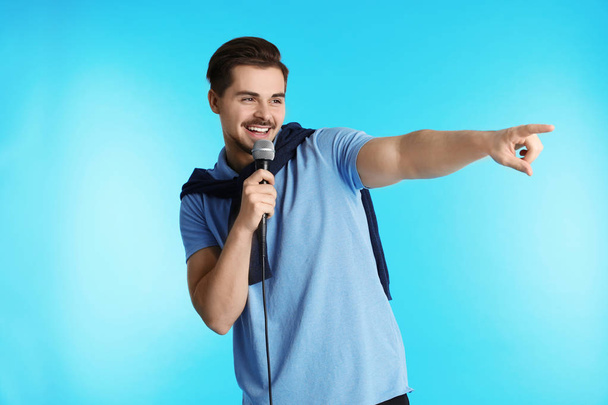 Young handsome man in casual clothes singing with microphone on white background - Foto, Bild