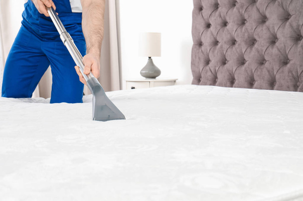 Man disinfecting mattress with vacuum cleaner, closeup. Space for text - Valokuva, kuva