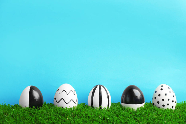 Line of painted Easter eggs on green lawn against color background, space for text - Zdjęcie, obraz