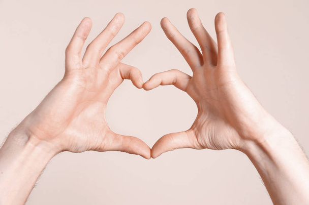 Young man making heart with his hands on light background, closeup - Φωτογραφία, εικόνα