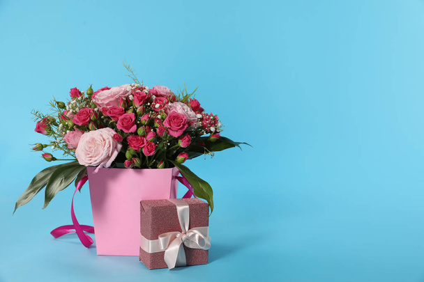 Beautiful bouquet of flowers and gift box on color background. Space for text - Zdjęcie, obraz