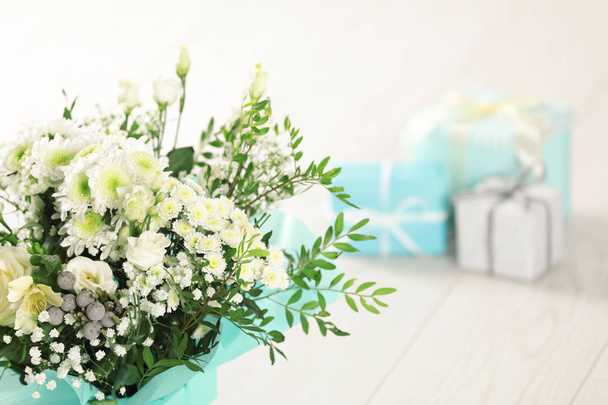 Beautiful bouquet of flowers and blurred gifts on background. Space for text - Foto, Bild