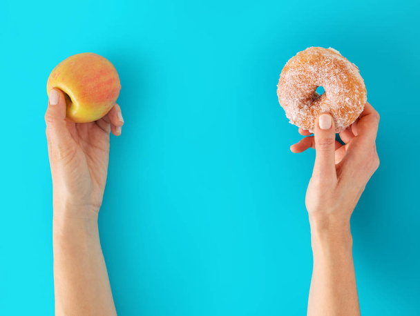 リンゴとドーナツには、両手ブルーの背景。ダイエットの概念. - 写真・画像