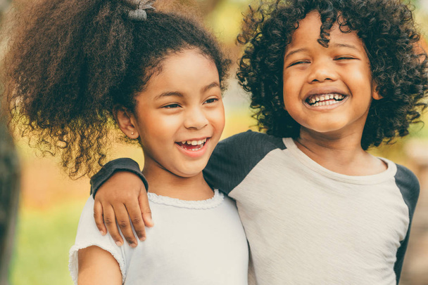 Счастливые мальчик и девочка в парке. Двое афроамериканских детей вместе в саду
. - Фото, изображение