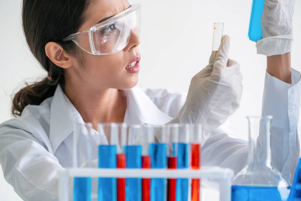 女性科学者は実験室で働き、試験管で生化学サンプルを調べる。科学技術研究開発研究概念. - 写真・画像