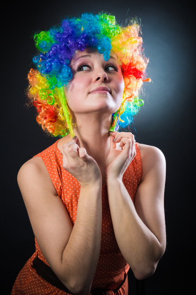 Woman in clown's wig smiling pulling fake hair on the sides - Foto, afbeelding