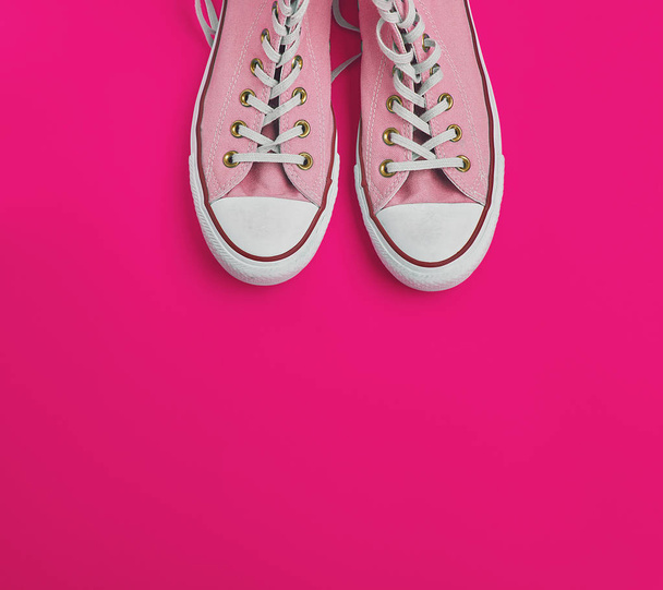 par de viejas zapatillas de deporte usadas de color rosa con cordones blancos sobre un fondo rosa, vista superior
 - Foto, imagen