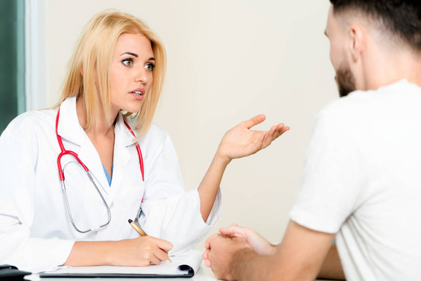 Ärztin spricht mit männlicher Patientin in Krankenhausbüro. Gesundheitswesen und medizinischer Dienst. - Foto, Bild