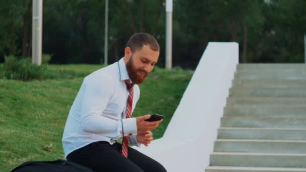 Attractive businessman looking at a mobile phone, feeling happy and leaving - Video, Çekim