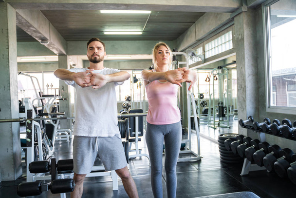 Young caucasian athletes couple strething warm up before exercise in gym - Foto, imagen
