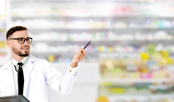 Young male pharmacist pointing at empty copy space for your text in the hospital. Medical healthcare and doctor staff service. - Photo, Image