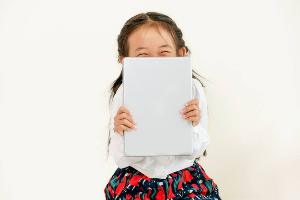 Pequeño niño feliz sobre fondo blanco con tableta. Estilo de vida infantil
. - Foto, Imagen