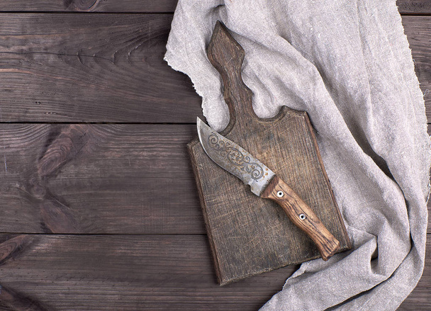 old wooden kitchen board and vintage knife on a brown wooden background, top view - Valokuva, kuva