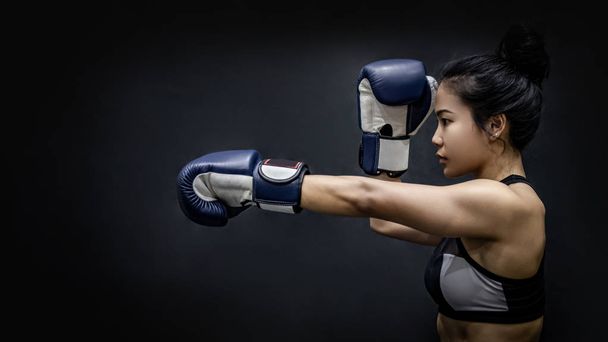 Азіатські дівчата боксер штампування з синім боксерські рукавички на чорному фоні в студії. Бойові мистецтва і жіночий кікбоксингу концепції - Фото, зображення