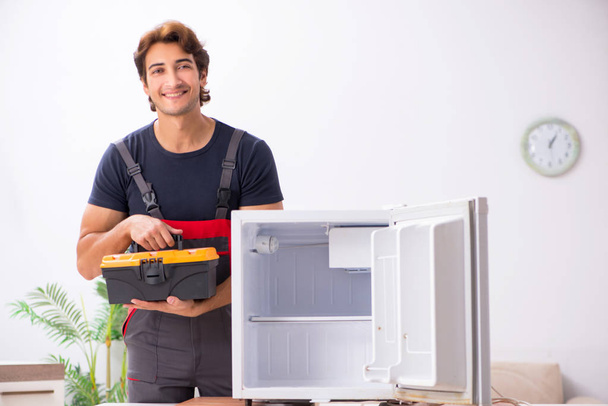 Fiatal jóképű vállalkozó javítása hűtőszekrény - Fotó, kép