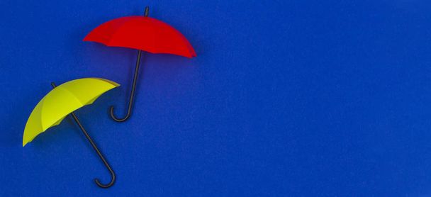 Kleine kleurrijke paraplu's op blauwe kleur achtergrond - Foto, afbeelding