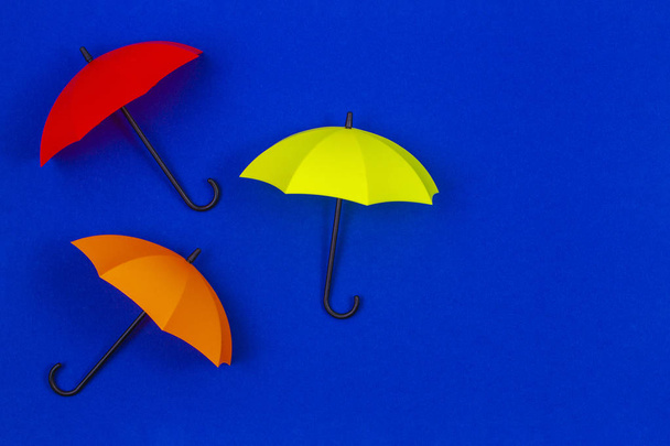 Kleine kleurrijke paraplu's op blauwe kleur achtergrond - Foto, afbeelding