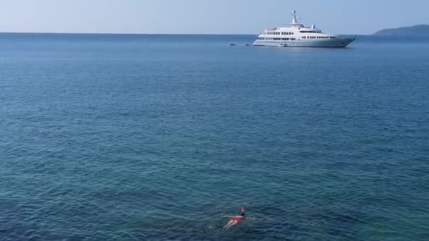 Jonge vrouw snorkelen in de blauwe tropische water dragen rode zwembroek met cruise schip aan de horizon. Travel concept - Video