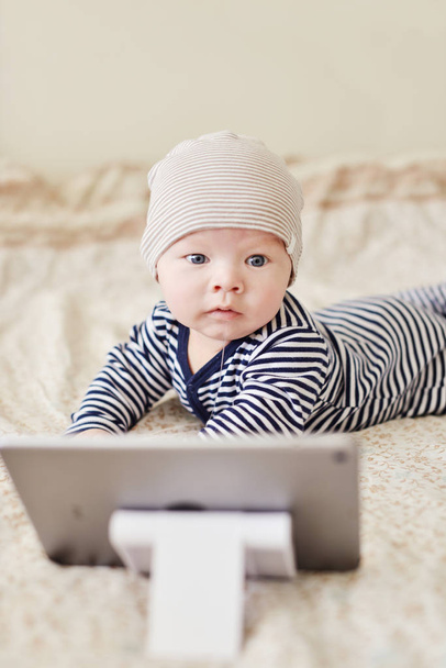 baby with tablet pc on the bed - Foto, imagen