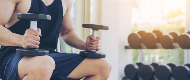 Muscular homem fisiculturista em treinamento fitness ginásio com halteres. Estilo de vida saudável e conceito de musculação
. - Foto, Imagem