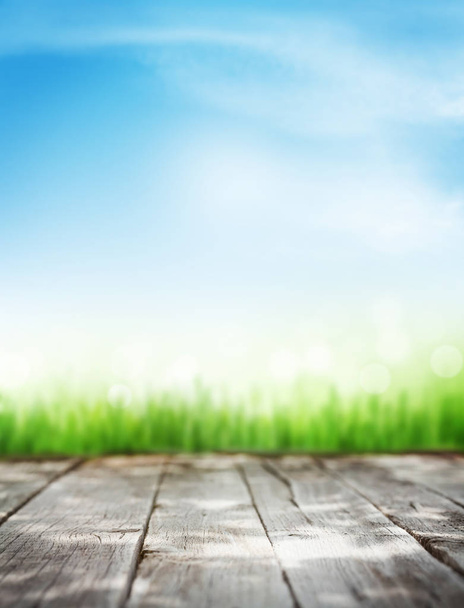 Abstracte zonnige zomer achtergrond met houten tafel, gras en een blauwe hemel. Kopiëren van ruimte voor uw product - Foto, afbeelding