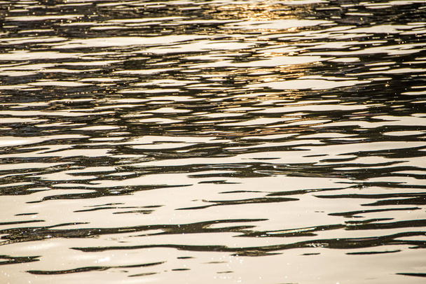 Water van de zee met de golven in warm zonsondergang licht - Foto, afbeelding