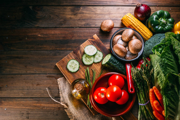 Valikoima tuoreita raaka vihanneksia ja astiat puinen keittiö pöytä
 - Valokuva, kuva