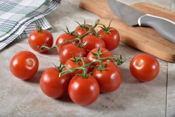Fresh pearl tomatoes on the vine near a cutting board - Foto, Imagen