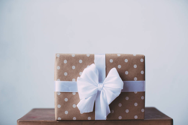 Stylish gift with a white ribbon on a wooden table. - 写真・画像