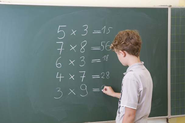 Little boy is doing some maths at a blackboard in school - Photo, Image