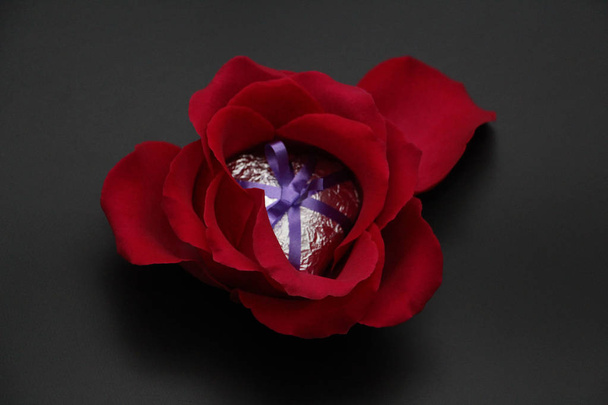 Metal heart surrounded by roses. Silver heart decorated with ribbon. Heart and roses on a dark background. - Foto, imagen