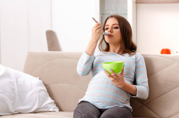 Young pregnant woman sitting on the sofa at home - Photo, Image